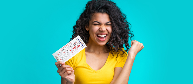 Mulher com cartela de bingo comemorando